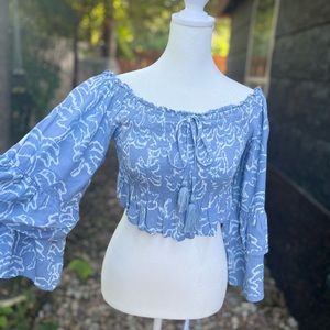 Blue crop top with flared designs on the bottom and on the sleeves